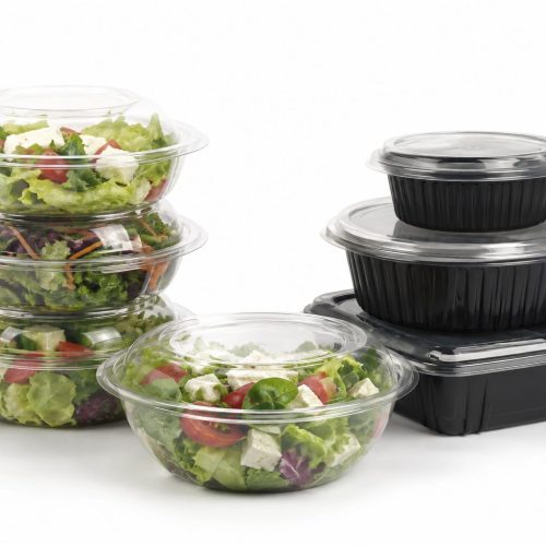 Clear salad bowls with domed lids beside black base containers
